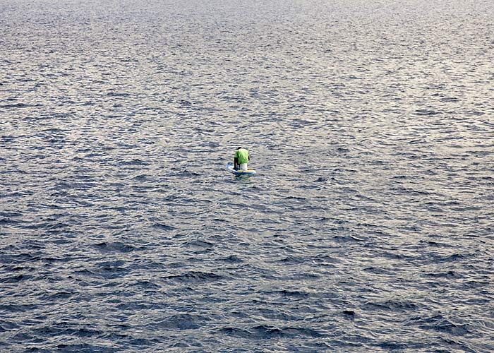 Man fishing on sailboard and bucket