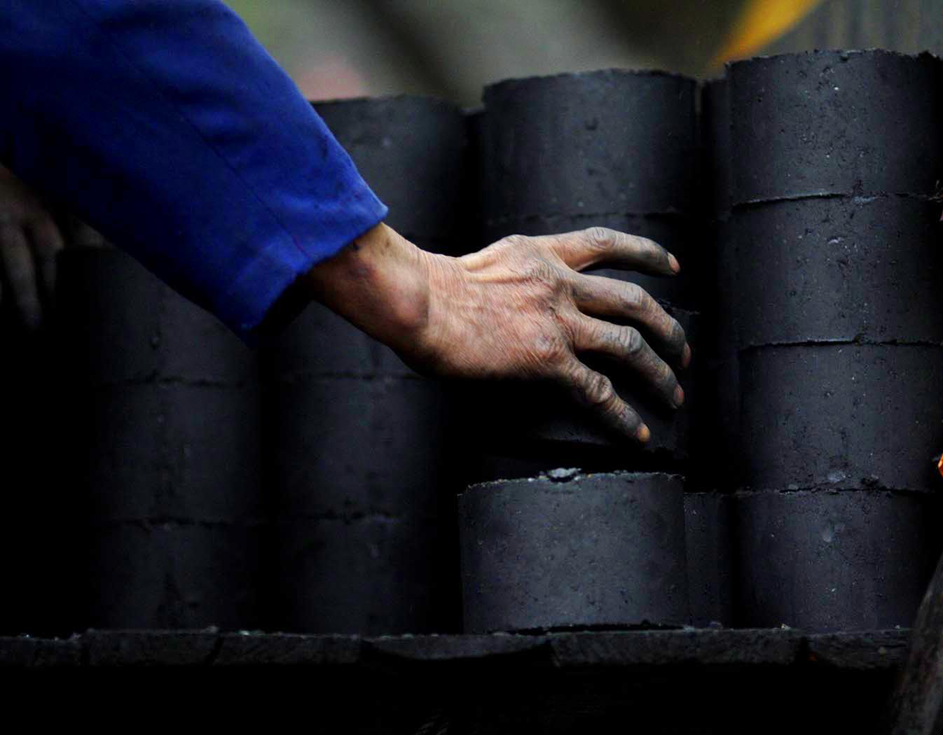 Stacking the compressed coal, one by one.