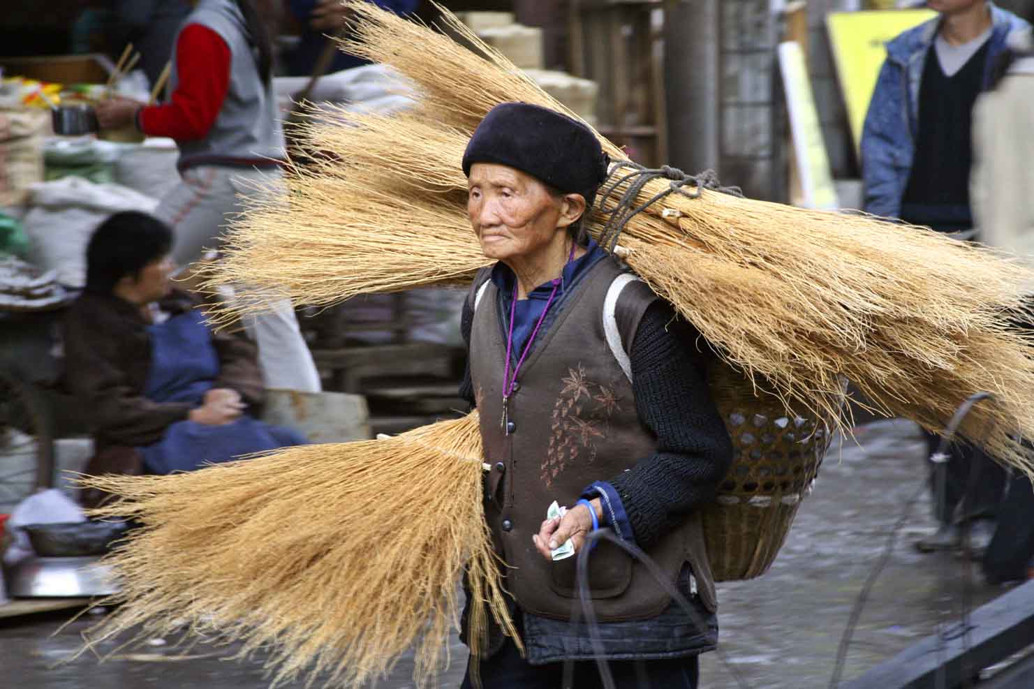 Elderly woman taking brooms to market. Jishou City, China.