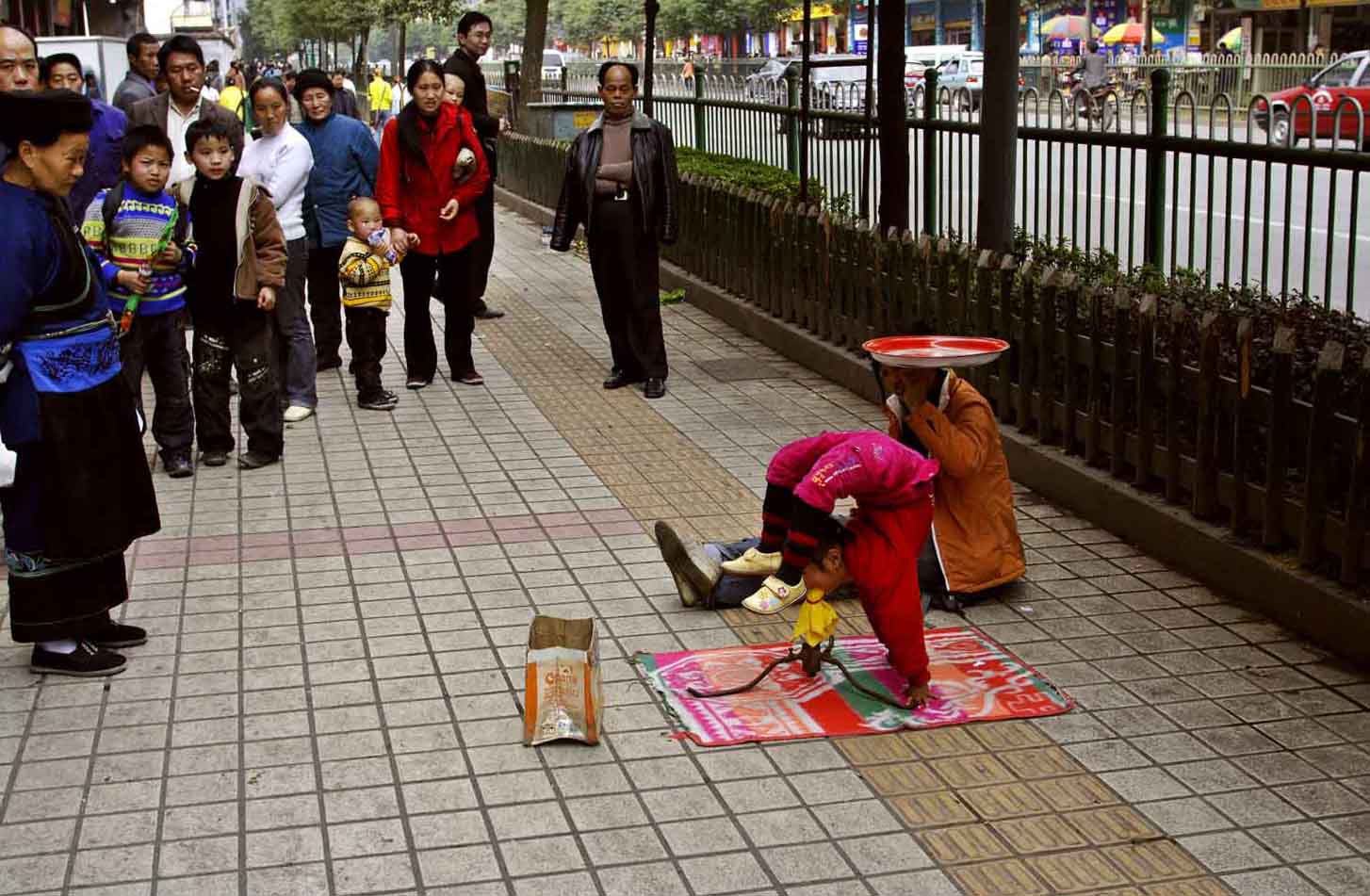 Girl balancing on mouth getting ready to spin while the girl in the background spins a plate. Jishou City, China.
