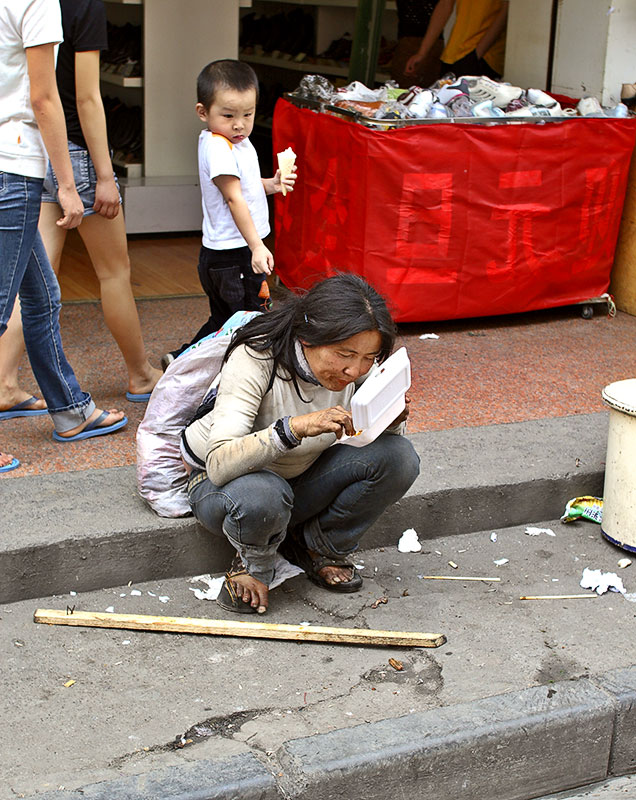 Eating from a container she found in the street.