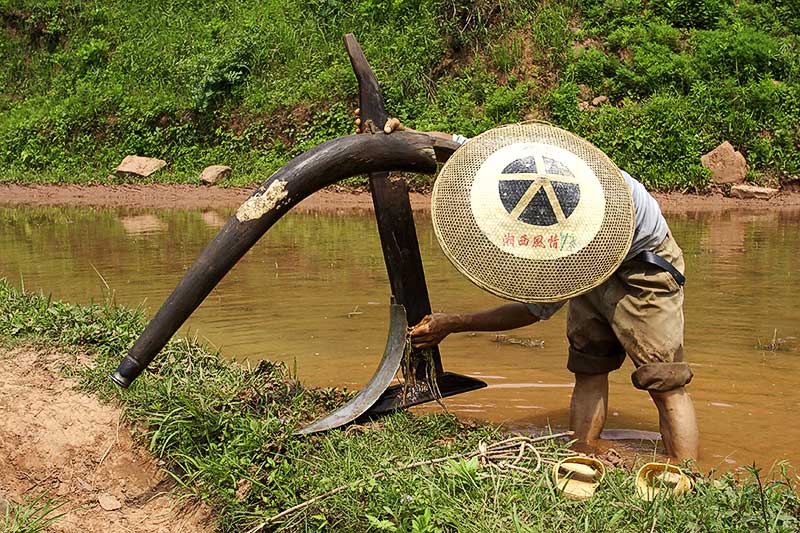 Washing the mud from his plow at the end of the day. Ping Shan Po. Wuling Mts.