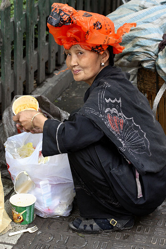 Sifting through the garbage, a plastic bag against the rain and Smiling.
