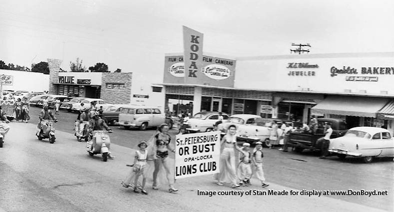 1950s - Opa-locka Arabian Nights Parade with a Value Market, Ernie Skogs Camera Store and Grables Bakery in the background