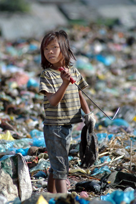 Young girl uses a tool for picking through the trash.