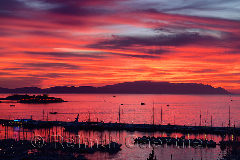 Red sky sunset at Kusadasi Turkey Harbour with Guvercin Adasi Island castle on the Aegean Sea with mountains of Samos Greece