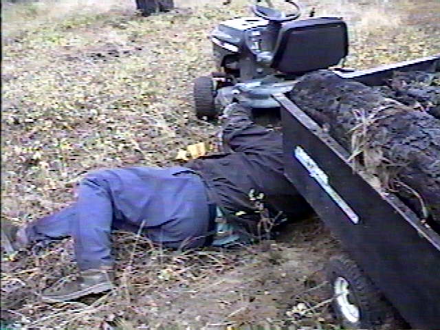 Dad putting drivebelt back on tractor after getting it stuck going up steep terrain with trailer being overloaded.jpg