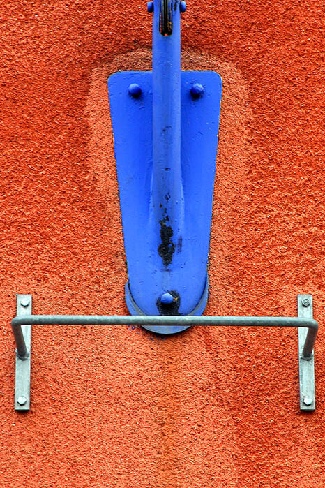 The blue flag pole and the red wall