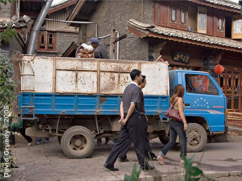LiJiang - old city.  Rubbish collection part 2. Seems the worker sorts it into baskets in the truck.