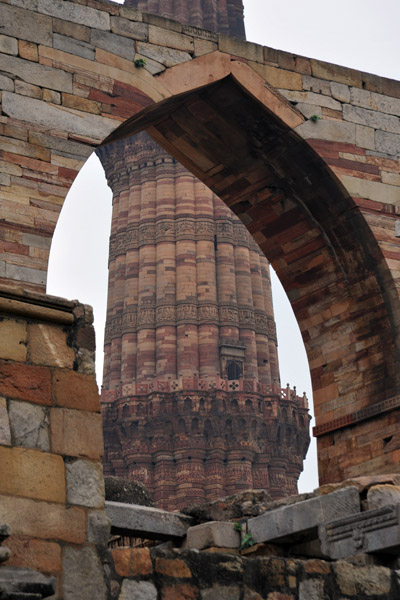 Part of the Qutb Minar through an arch of the mosque