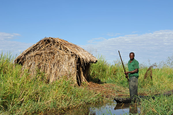 Mokoro in a shallow channel by a grass hut, Bangweulu Swamps