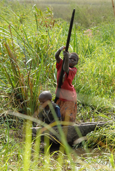 Girl poling a mokoro with her little brother