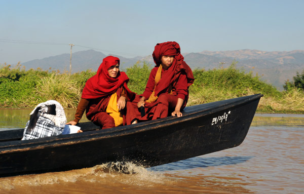 A pair of monks in front of a long boat with their heads wrapped