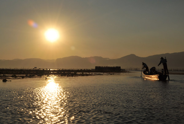 Boat paddling away from Myanmar Treasure Resort Inle  as sunset nears