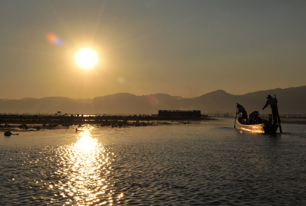 Boat paddling away from Myanmar Treasure Resort Inle as sunset nears