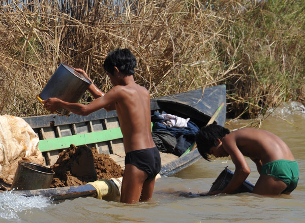 Boys collecting dirt from the river bottom, probably for use on a floating farm