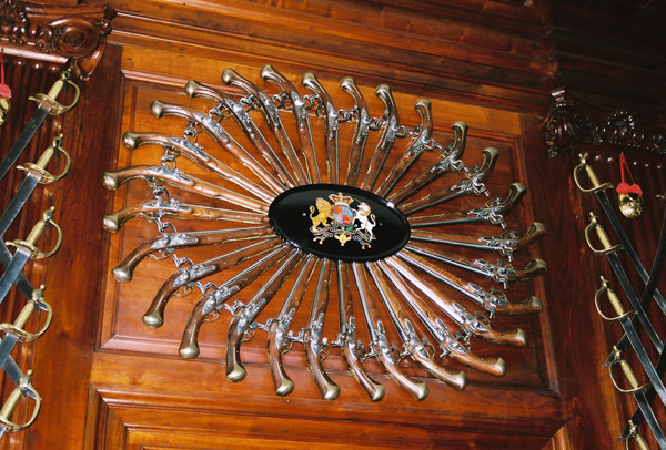 A circle of flintlock pistols around the British coat-of-arms