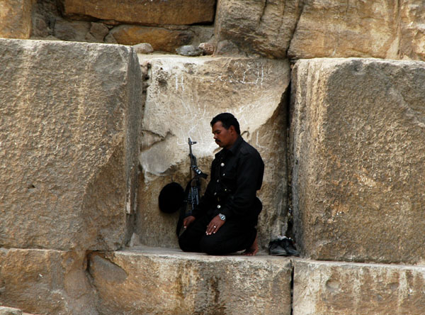 Well armed tourist policeman praying in a niche in the Great Pyramid