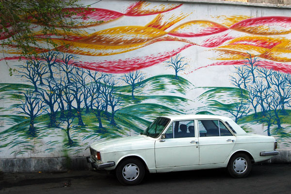 Iranian car parked in front of a mural in central Tehran