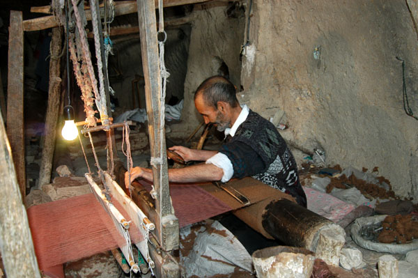 Weaver at work on a loom making a rough heavy cloth