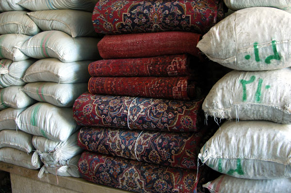 Carpets stacked between bags of other goods, Bazar-e Vakil