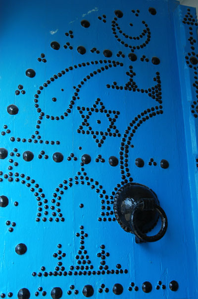 Tunisian studded blue door with various symbols