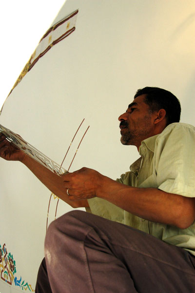 Painter applying stenciled artwork to a dome under restoration
