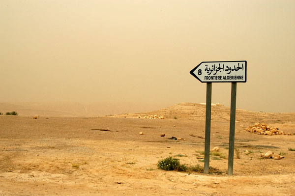 Sign pointing across the desert to the Algerian border