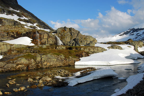 Snowy stream and small waterfalls along Route 63 descending from Djupvann to Geirangerfjord