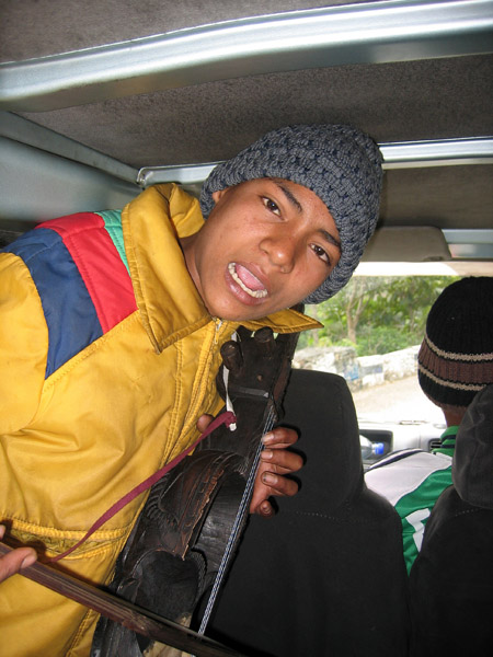 On board entertainment - boy playing a traditional instrument called a Kutumba