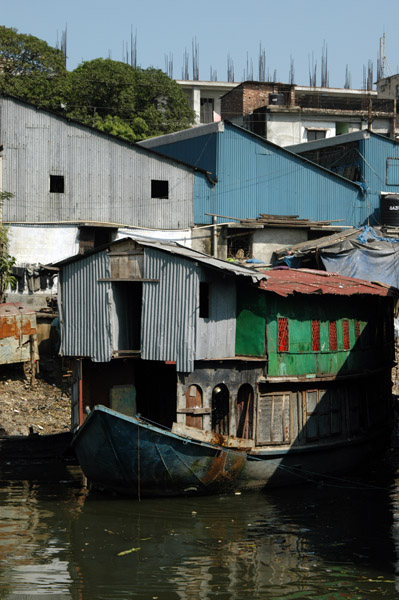 An old houseboat with what look like squatters shacks built on top of it