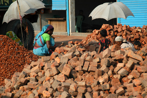 Bangladeshi women breaking old bricks into tiny bits