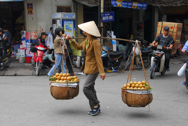Vietnamese woman with fruit baskets on a pole, Old Quarter, Hanoi