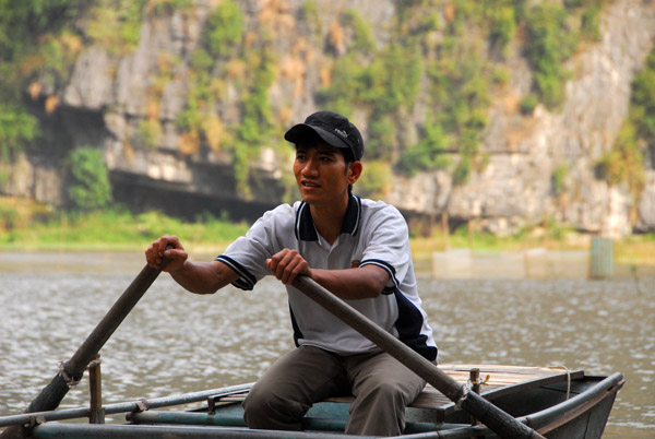 Young man rowing a boat, Tam Coc