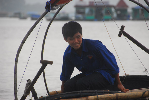 Boy from the floating village hoping to make some extra money rowing tourists around Cat Ba Harbor