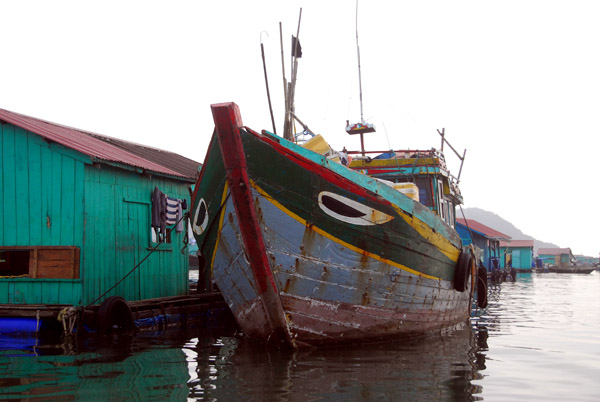 Fishing boat tied up at one of the floating village huts, Cat Ba Harbor