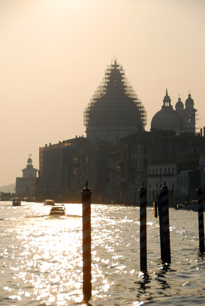 Sun shining on the Grand Canal with a sillhouette of the scaffolding-encrused dome of the Basilica of Santa Maria della Salute