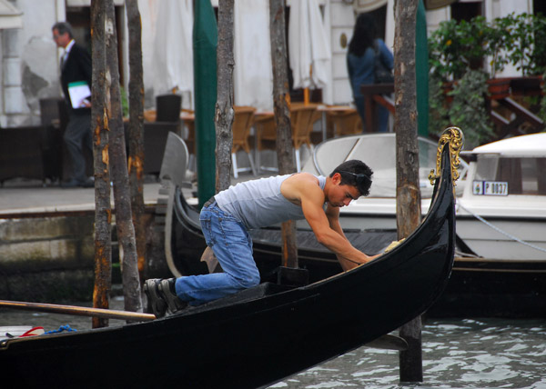 Young man polishing a Venetian gondola
