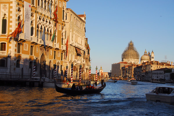 Venetian Gondola on the Grand Canal in front of the Palazzo Cavalli Franchetti with the domes of Santa Maria della Salute