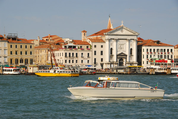 Classic wooden motorboat cruising Canale della Giudecca in front of Santa Maria d. Piet on Riva degli Schiavoni