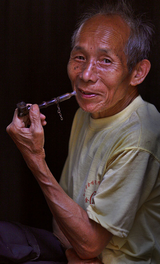 Kam elder with traditional bamboo and ceramic pipe.