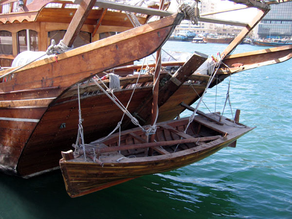 Small boat hanging off the stern of a wooden dhow, Dubai Creek