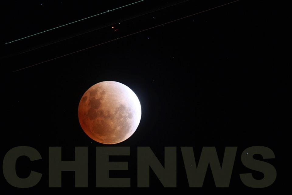 Plane flying over a full lunar eclipse (the streaks of light came from the planes wingtips)  on the night of 11 Dec 2011