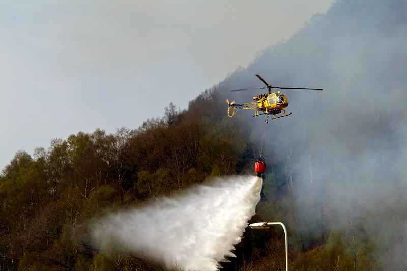 Forest fire buring close to the main road through the valley