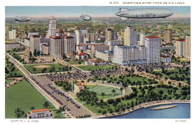 1930s - two Goodyear blimps and either the Navys USS AKRON or the USS MACON rigid airship over downtown Miami