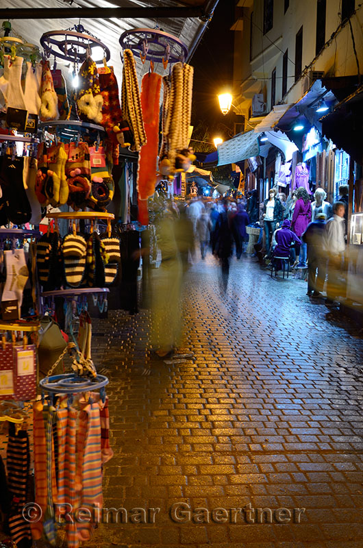 Blurred shoppers and shops on a rainy night in Fes el Bali Medina Morocco