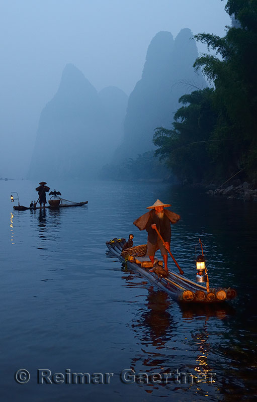 Two early morning Cormorant fishermen on bamboo rafts on Li river near Xingping China