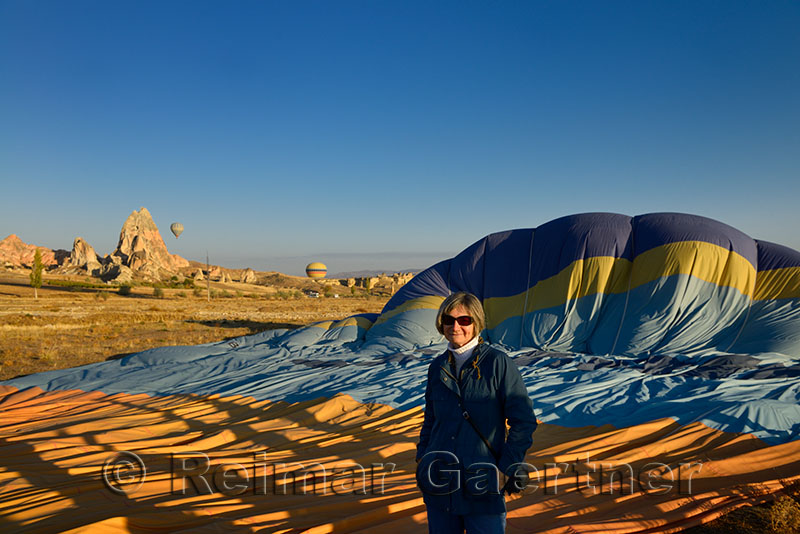 Tourist standing beside a deflated hot air balloon on the ground in Cappadocia Turkey