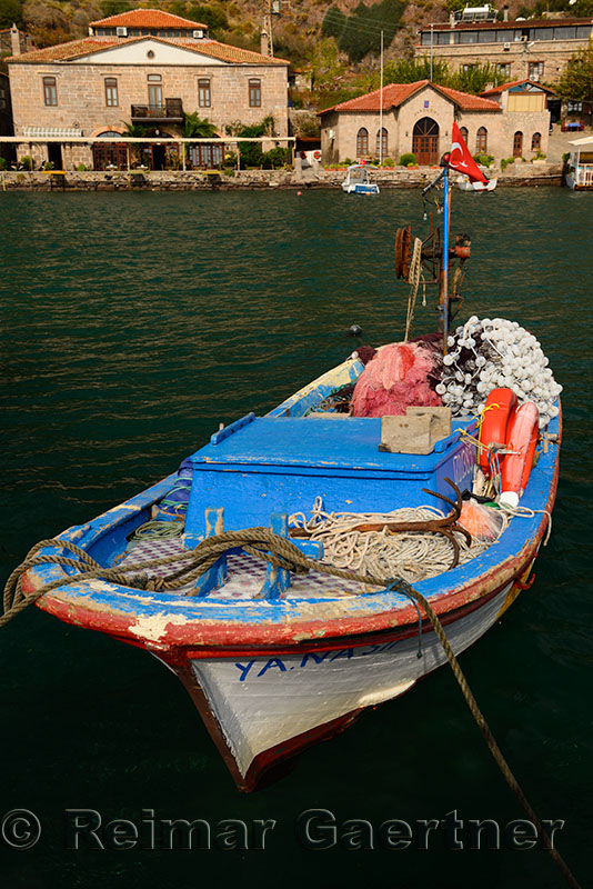 Fishing boat with hotels and police station in the hamlet of Assos Iskele or Behram Turkey