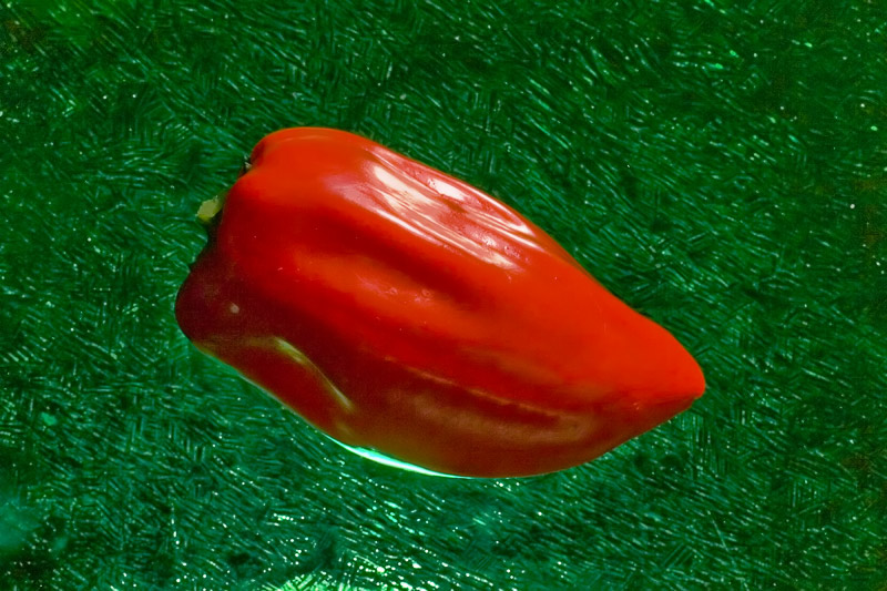 Red Pepper Hovering Over Green Glass Plate *
